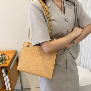 Brown crocodile texture shoulder bag with gold chain strap shown on a female model