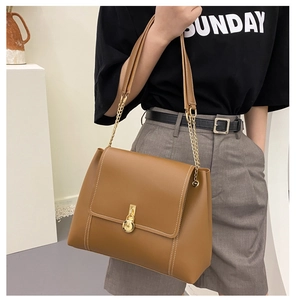 Detail of caramel leather shoulder bag with gold circular lock and white stitching