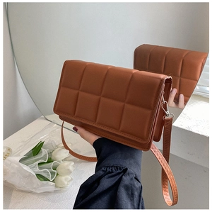 Detailed close-up of brown quilted crossbody bag with stylish grid pattern in soft lighting