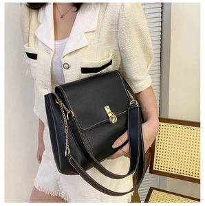 Detail of black PU crossbody bag featuring white contrast stitching and gold twist lock
