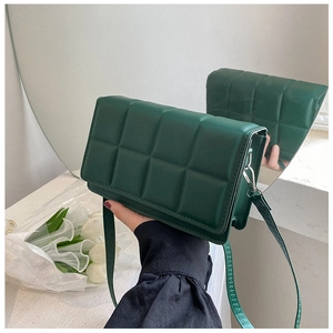 Detailed macro view of dark green quilted faux leather crossbody bag with silver buckles