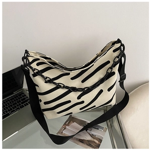 Detail of zebra print canvas tote featuring wide fabric strap and black acrylic chain