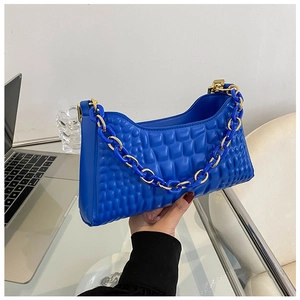 Detail of blue quilted bag showing modern square textures and thick chain handle decoration