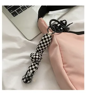 Close-up of black and white checkered fabric bag charm with knot detail and black clip