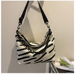 Detail of a zebra stripe canvas hobo bag featuring a black wide strap and chunky chain link