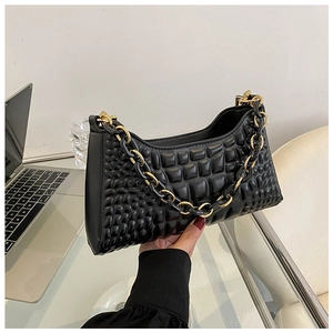 Detail of black underarm bag featuring 3D quilted bubble texture and chunky gold chain