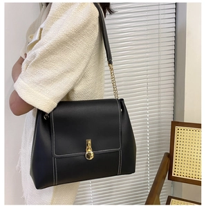 Close-up of black crossbody bag featuring white contrast stitching and gold metal buckle