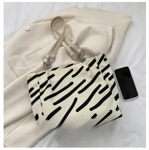 Detail showing zebra striped canvas tote bag size compared to a black smartphone