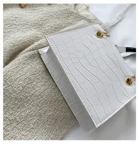 Close-up of white crocodile pattern leather bag with golden metal eyelet and buckle