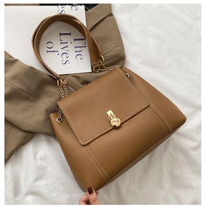 Detail of caramel leather bag featuring contrast stitching and a gold circular buckle closure