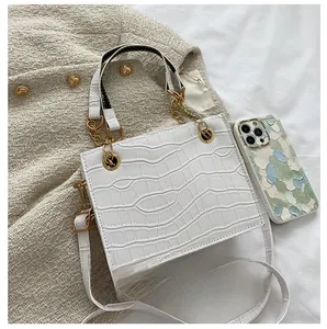 Detailed top view of white croc-embossed square bag with chain and size contrast