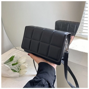 Detail of black quilted faux leather crossbody bag with elegant square pattern texture