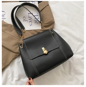 Detail of black crossbody tote bag with white stitching and golden metal lock