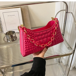 Detail of hot pink shoulder bag with square embossed texture and chunky gold chain strap