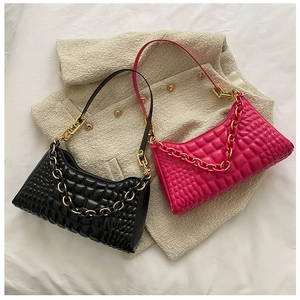 Detail of contrast color baguette bags with embossed texture and gold chain straps