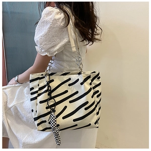 Detail showing hand-painted black stripes on a canvas tote bag with a checkerboard bow