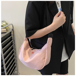 Adjustable shoulder strap detail on a pink waterproof nylon half-moon crossbody bag