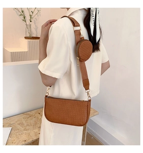 Detail of a brown embossed underarm bag with a wide strap and a small round coin pouch
