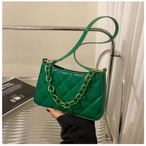 Détail du sac bandoulière vert matelassé avec chaîne dorée et texture cuir lisse