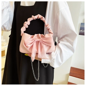 Détail du sac rose avec nœud, poignée froncée et bandoulière en chaîne argentée