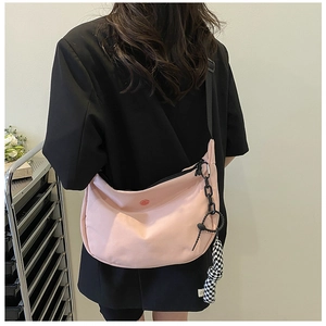 Pink nylon crossbody bag with black adjustable strap and decorative checkered pendant