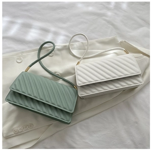 Detailed shot of sage green and beige quilted baguette bags on a white blazer