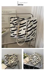 Detail view of large white canvas tote with zebra stripes and metal chain handle