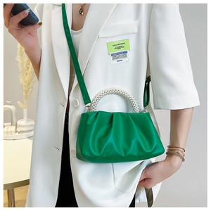 Detail of emerald green ruched handbag featuring a pearl bead handle and leather strap
