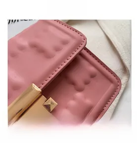 Close-up of pink quilted chain bag with gold metal square buckle and bubble texture