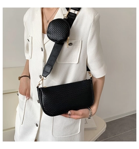 Close-up of black woven shoulder bag with a small round coin purse on wide strap