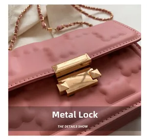 Macro view of pink leather bag with biscuit embossed texture and gold hardware lock