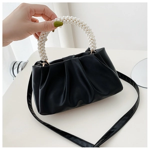 Detail of black pleated cloud bag with elegant white pearl handle and PU leather texture