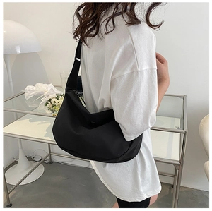 Detail of minimalist black nylon crescent bag with adjustable wide strap and smooth zip