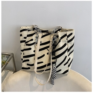 Close-up of zebra stripe canvas tote with silver chain handles and checkered charm