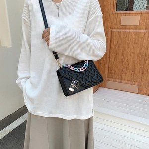 Quilted black crossbody bag with a chunky iridescent resin chain and gold clasp lock