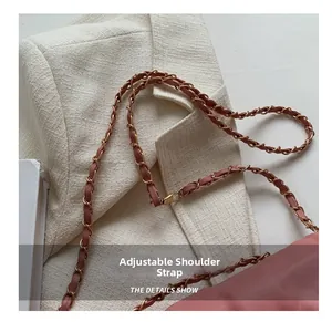 Detail of adjustable pale pink leather and gold metal chain strap on small crossbody bag
