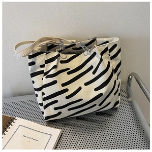 Detail of striped canvas tote bag with metal chain handle and magnetic clasp closure