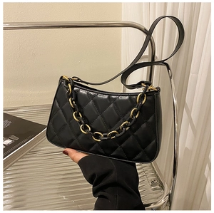 Détail d'un sac bandoulière noir matelassé avec chaîne dorée et base arrondie