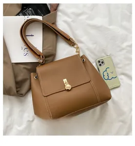 Detail of caramel leather shoulder bag with round golden metal buckle and chain strap