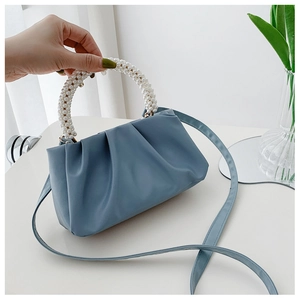 Detail of blue pleated cloud bag featuring elegant white pearl bead handle and soft texture