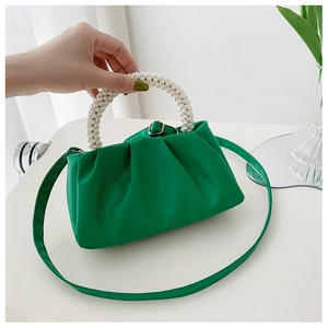 Detail of green ruched cloud handbag featuring luxury white pearl beads handle texture
