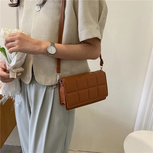 Brown quilted crossbody bag with a square pattern and leather strap on a model