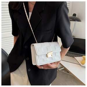 Detail of white PU leather crossbody bag with geometric embossed pattern and gold clasp