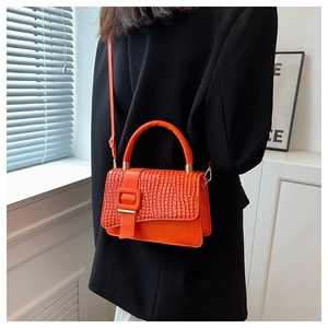 Details der orangefarbenen Tasche mit Krokodilmuster, Metallakzenten und Schultergurt