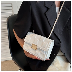 Close-up of white leather crossbody bag with textured square pattern and gold metal lock