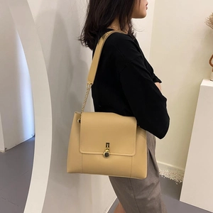 Elegant beige leather crossbody bag with gold chain strap and metal lock closure