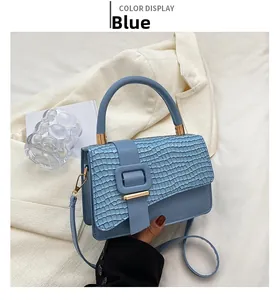 Detail der blauen Krokostruktur-Klappe und goldener Schnalle der Schultertasche