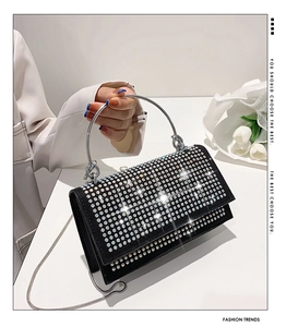 Detail of black rhinestone evening clutch bag with round metal handle and chain strap