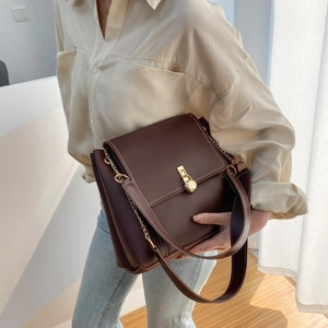 Caramel brown structured crossbody tote bag with gold spherical clasp and chain strap