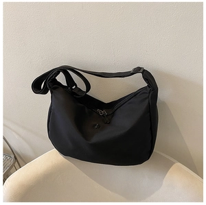 Detail of black oxford nylon hobo bag with adjustable strap on a white chair